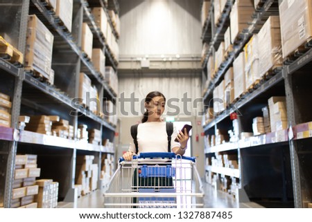 Woman use cart for shopping furniture in warehouse