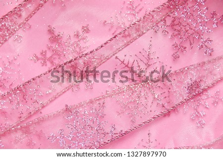 Abstract textured background of pink net ribbon with glitter snowflakes