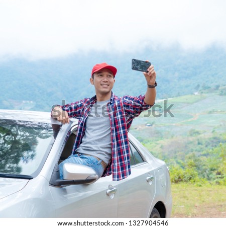 Freedom - enjoying road trip travel man on summer day. man sitting on his car and taking photo while traveling by car with joy in holiday