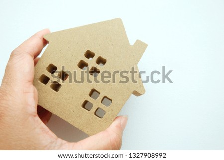 Woman hand holding a mini wooden house on white background.