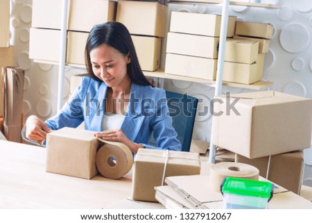 The young  Asia Businesswoman makes parcel. She makes it for order online. She is happy and smiles.Gift,Business,work woman,Freelance,happy,pleasure.Photo concept work and Shopping.