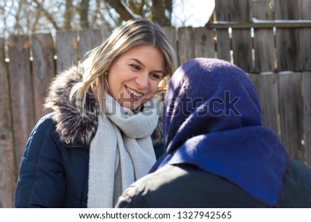 Picture of smiling young woman spending time with old grandmother outdoor