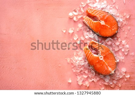 Fresh salmon slices on ice cubes over slate, stone or concrete background.Top view with copy space.