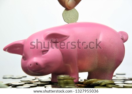 hand putting fifty pence UK coin into  piggy bank