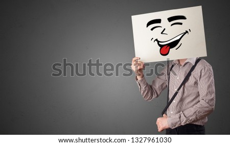 Casual person holding a paper with cool emoticon in front of his face