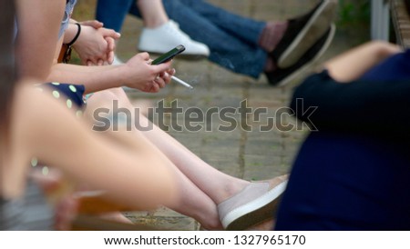 Smoking woman with smartphone outdoors. Young woman smoking cigarette and using her smartphone outside.