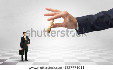 Small businessman fighting against big chessman on a big hand with chess board concept