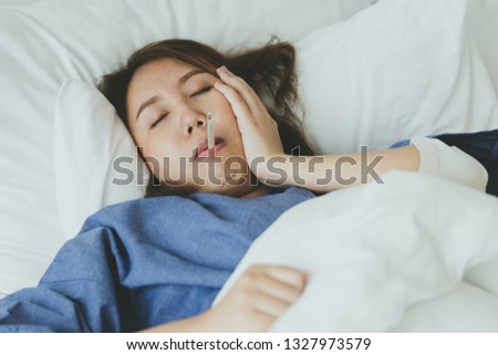 Asian Beautiful Woman Hypothermia has been measured by fever. Lie on the bed to give a body of rehabilitation. The concept of medical care to patients at home by yourself. Royalty-Free Stock Photo #1327973579