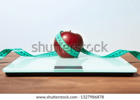 The concept of healthy diet, fitness and weight loss. Scales, measure tape, oatmeal, apple, a glass of juice on the table. 