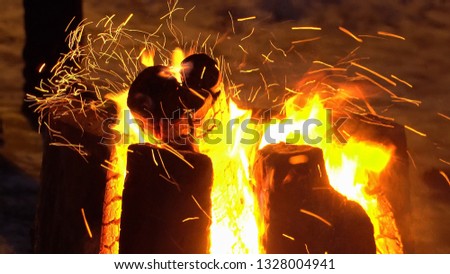 Fire flames with sparks at night. Campfire in close-up view. The Swedish bonfire as a burning tree stump in the open air. 