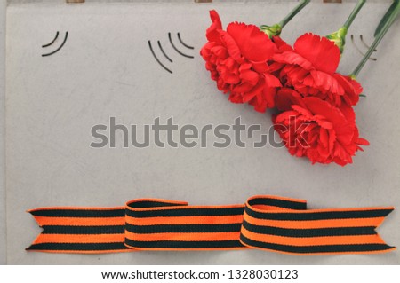 May 9 Victory day card. Red carnations and St. George ribbon on the background of an old photo album. Day of memory and military glory.