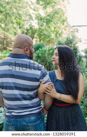 Two people in love are standing on a beautiful alley in the park.
