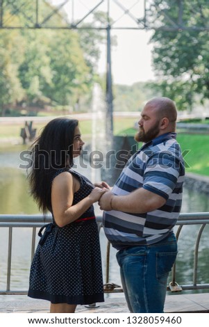 Two people in love are standing at the idle fountain in the park.