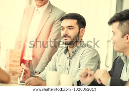Group of young business people working, communicating while sitting at the office desk together with colleagues. Business people has stategic planning with wood block in office. Business concept.