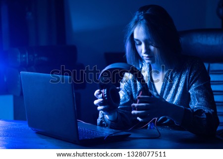 The girl puts on headphones. Remote work. A woman works through the Internet. The girl listens to music at the computer.