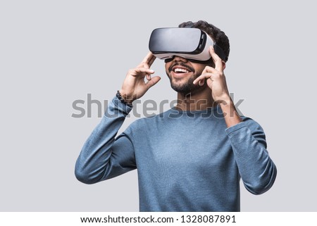 Young man using virtual reality headset. Isolated on gray background studio portrait. VR, future, gadgets, technology, education online, studying, video game concept Royalty-Free Stock Photo #1328087891