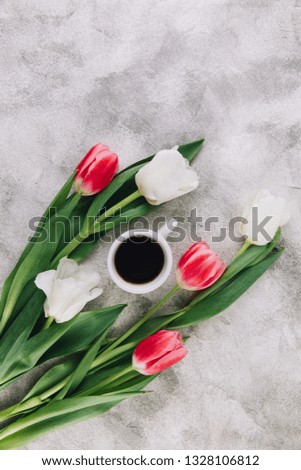 Fresh tulips flowers and cup of coffee on stone table. Top view with copy space