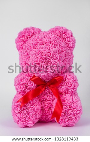 Pink teddy bear toy of foamirane roses. Red stripe on teddy neck. Stock photo isolated on white background. Gift on holiday for women.