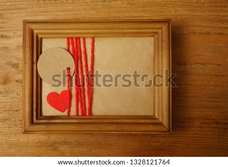Blank photo frame with vintage gift box wrapped in craft paper and tag on old wooden table background. flat lay. top view