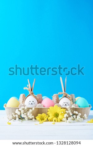 Easter colored eggs in paper tray with decorationd on blue background