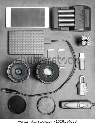 Workspace of photographer. Top view with black table, photo flas, lens, smartphone, remote control, compact disk and battery charger. 