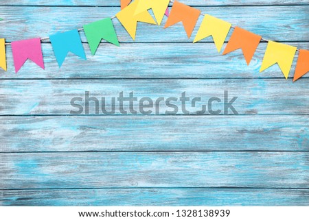 Colorful paper flags hanging on blue wooden background