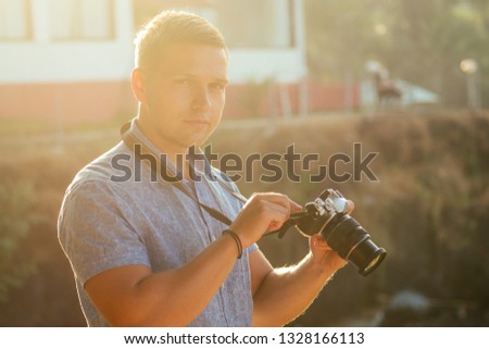 handsome and confident man photographer with a large professional camera taking pictures photo shooting on the beach.photo session on summer holiday on the background of green tropical trees