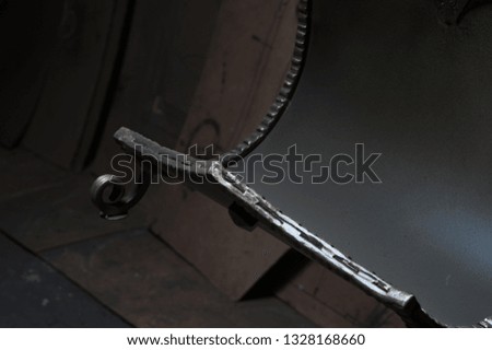 Close up of door metal partitions detail. Part of metal armature shot on blacksmith workshop grey and brown background. Metal detail shot of metal door.