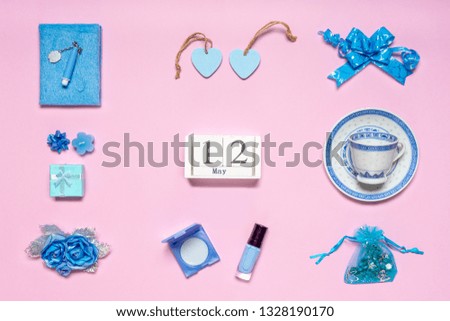 Stylish feminine accessories, flowers, cosmetics, gifts and decorative items in blue pastel colors on pink background. Calendar date May 12. Greeting card for mother's day in 2019. Flat lay, top view