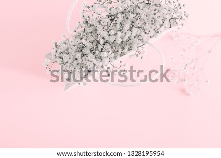 Flowers composition minimal. White flowers gypsophila in white paper bag on pastel pink background. Valentine's Day. Birthday, Happy Women's Day. Flat lay, top view, copy space 