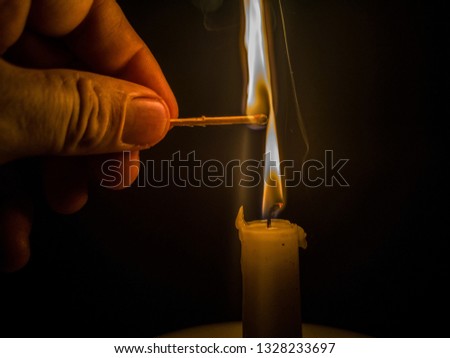 Matches burning to light a candle on black background