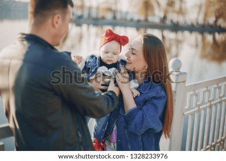beautiful mother with her husband and small daughter in the spring park near river