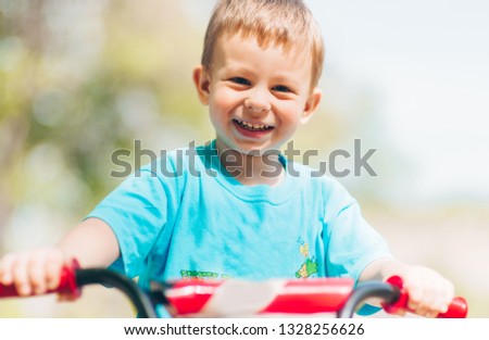 Precious blond toddler is happy in the park while driving a bicylce