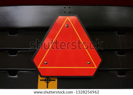 reflective orange triangular sign emergency stop on a tractor hanging on the back