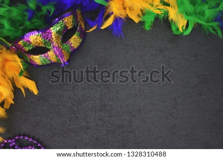 Festive Mardi Gras Venetian Carnival Mask and Colorful Feather Boa on Blackboard Background with Copy Space for New Orleans Party or Halloween Holidays, Shot from Directly Above
