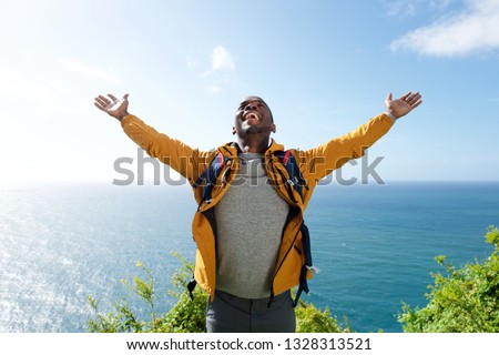 Portrait of african american male hiker with backpack and arms open 