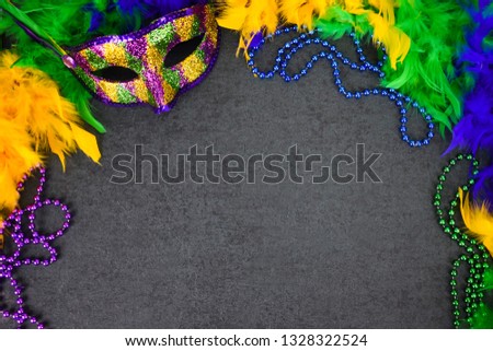 Festive New Orleans Mardi Gras Colorful Venetian Carnival Mask, Beads and Feather Boa Over Black Background with Copy Space for Mardi Gras Celebration or Halloween Holiday, Shot from Directly Above