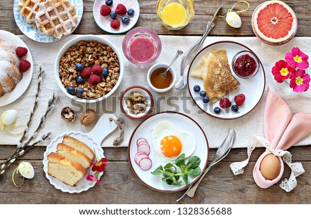 Easter festive breakfast or brunch set served on rustic wooden table. Overhead view, copy space