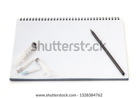 Needles for medical injections are on the notebook isolated on white background. There is free space for your text or sign.