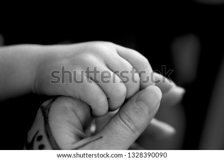 Mother holding her childs hand, tattoo on mothers hand