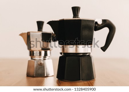 Steel and black geyser coffee makers on wooden table. Alternative coffee brewing method. Stylish accessories and items for alternative coffee