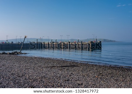 Largs Pier and the Old Harbour Wall with its Leaning Warning Post on a Bright February day on the West Coast of Scotland.