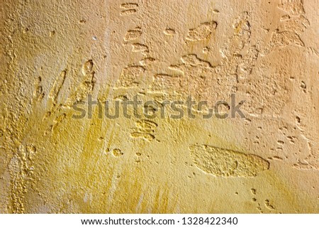 Close-up of colorful golden bronze plastered uneven stucco wall. Abstract texture, chaotic copy space background. Decorative grunge space.