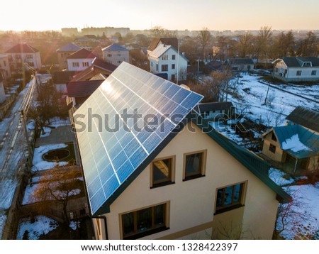 Aerial view of new modern two story house cottage with blue shiny solar photo voltaic panels system on the roof. Renewable ecological green energy production concept.