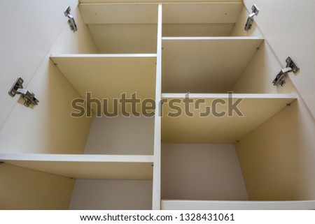 Interior of white plastic cabinet or clothing wardrobe with many empty shelves with open doors. Furniture design and installation.
