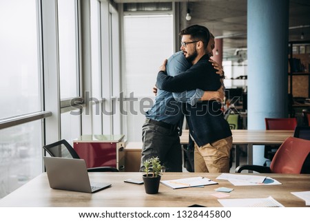 Two business colleagues hug and congratulate each other with success in their office Royalty-Free Stock Photo #1328445800