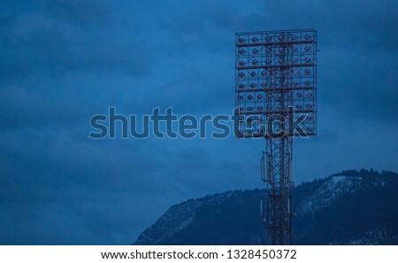 Big vintage stadium lights on a lighting tower in an off state. Evening setting with stadium lights turned off
