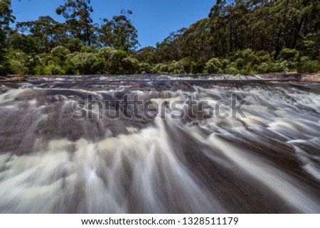 Blurred water flow through rapids on a river in a forest