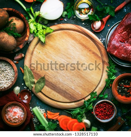 Fresh organic vegetables, ingredients, spices and meat for soup or broth on vintage kitchen table background with rustic wooden cutting board. Top view, place for text. 