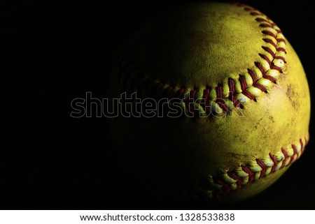 Yellow softball on black background.